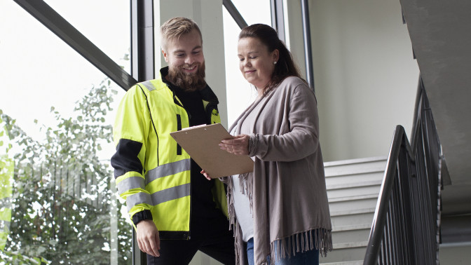 Konsultti ja nainen katsovat asiakirjaa portaassa.