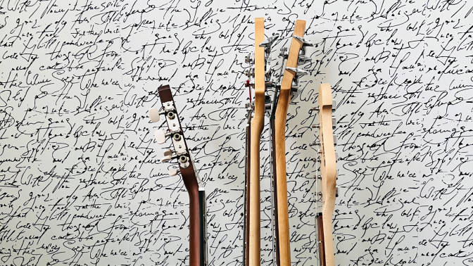 Kaksi kitaraa ja kaksi bassoa telineessä seinää vasten.