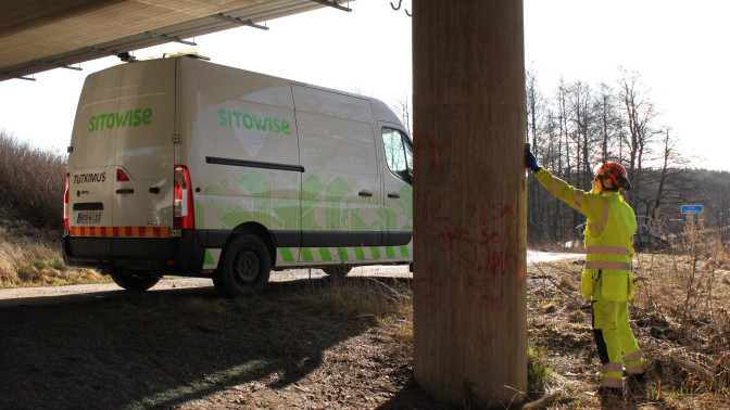 Sitowisen asiantuntija ja pakettiauto sillan alla tutkimuksia suorittamassa.