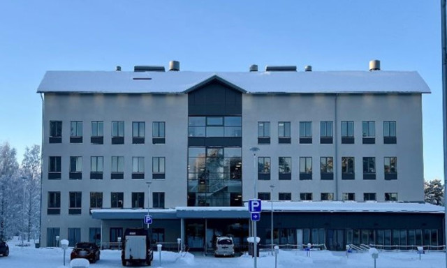 Talvinen Innocum toimistorakennus, jonka edessä on pysäköityjä autoja ja luminen piha.