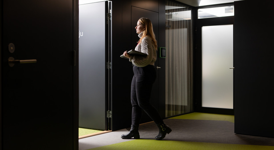 Emilia Rantanen kävelee hämärän toimiston käytävällä kohti valoisaa huonetta.