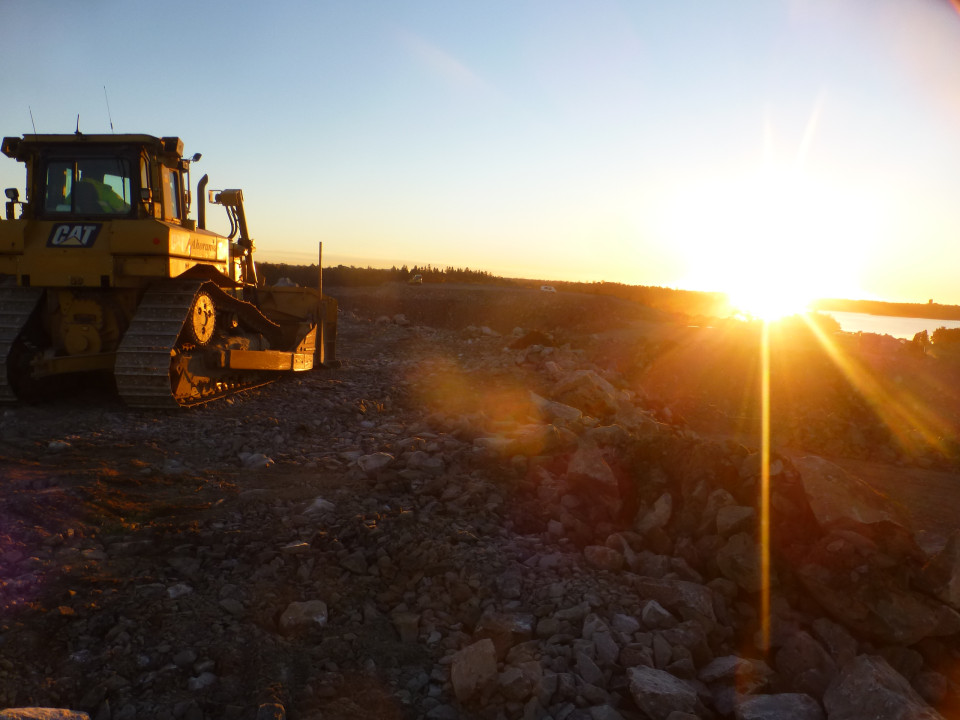 Traktori työmaalla auringon laskussa.