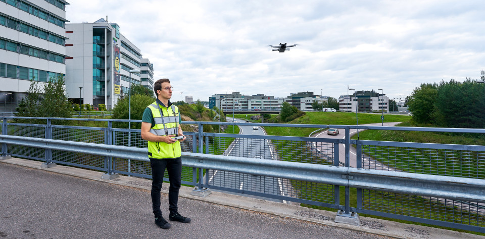 Kristo Vedenoja lennättää dronea sillalla kaupunkimaisemassa.