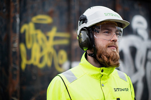 An employee wearing a hard hat and ear protection on a construction site
