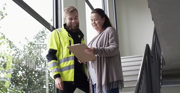 Konsultti ja nainen katsovat asiakirjaa portaassa.