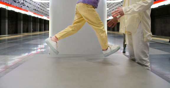 Lapsi hyppää aikuisen syliin metroasemalla.