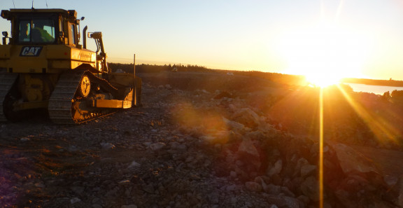 Traktori työmaalla auringon laskussa.