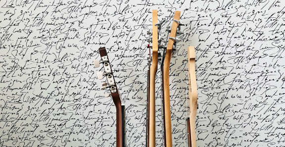 Kaksi kitaraa ja kaksi bassoa telineessä seinää vasten.