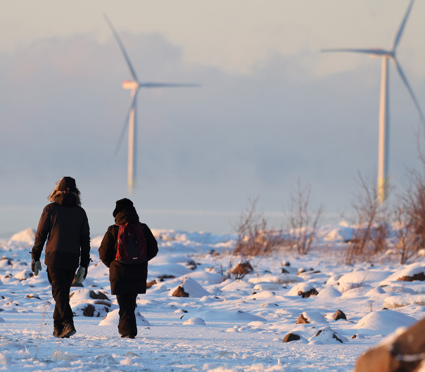 Kaksi henkilöä kävelee lumisissa maisemissa.
