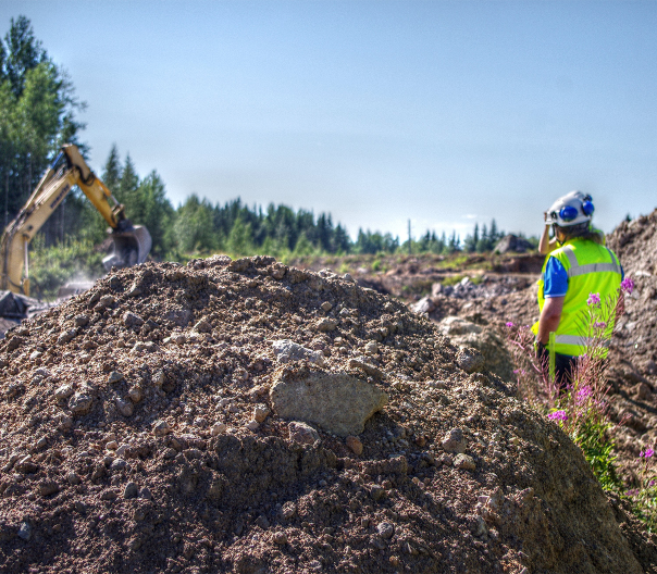 Kaivinkone ja henkilö työmaalla.
