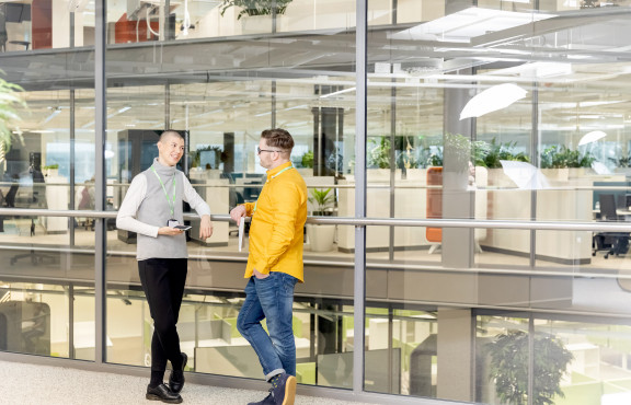 Kaksi henkilöä keskustelee toimistotilassa avoimessa ja modernissa työympäristössä