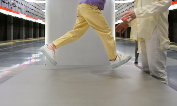 Lapsi hyppää aikuisen syliin metroasemalla.