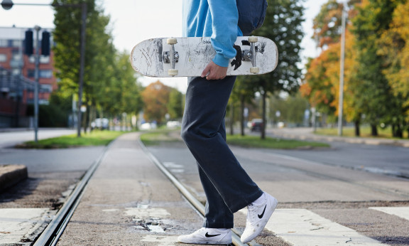 Henkilö kävelee suojatiellä rullalauta kädessä.