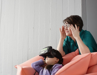 Lapsi ja aikuinen katsovat samaan suuntaan, lapsella on VR-lasit päässään.