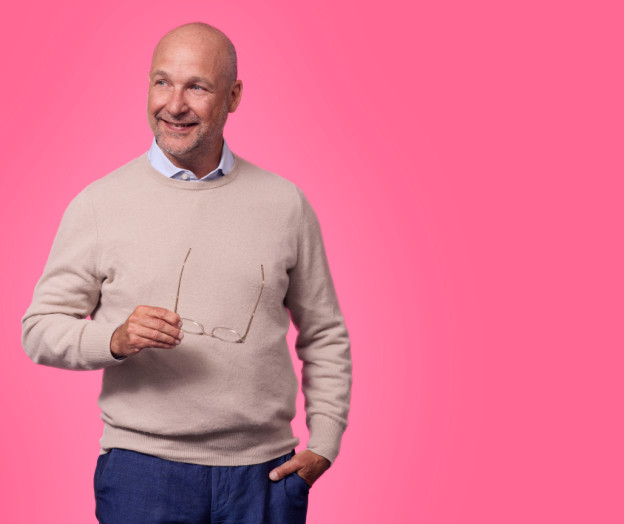 mies hymyilee kuvassa ja pitää silmälaseja